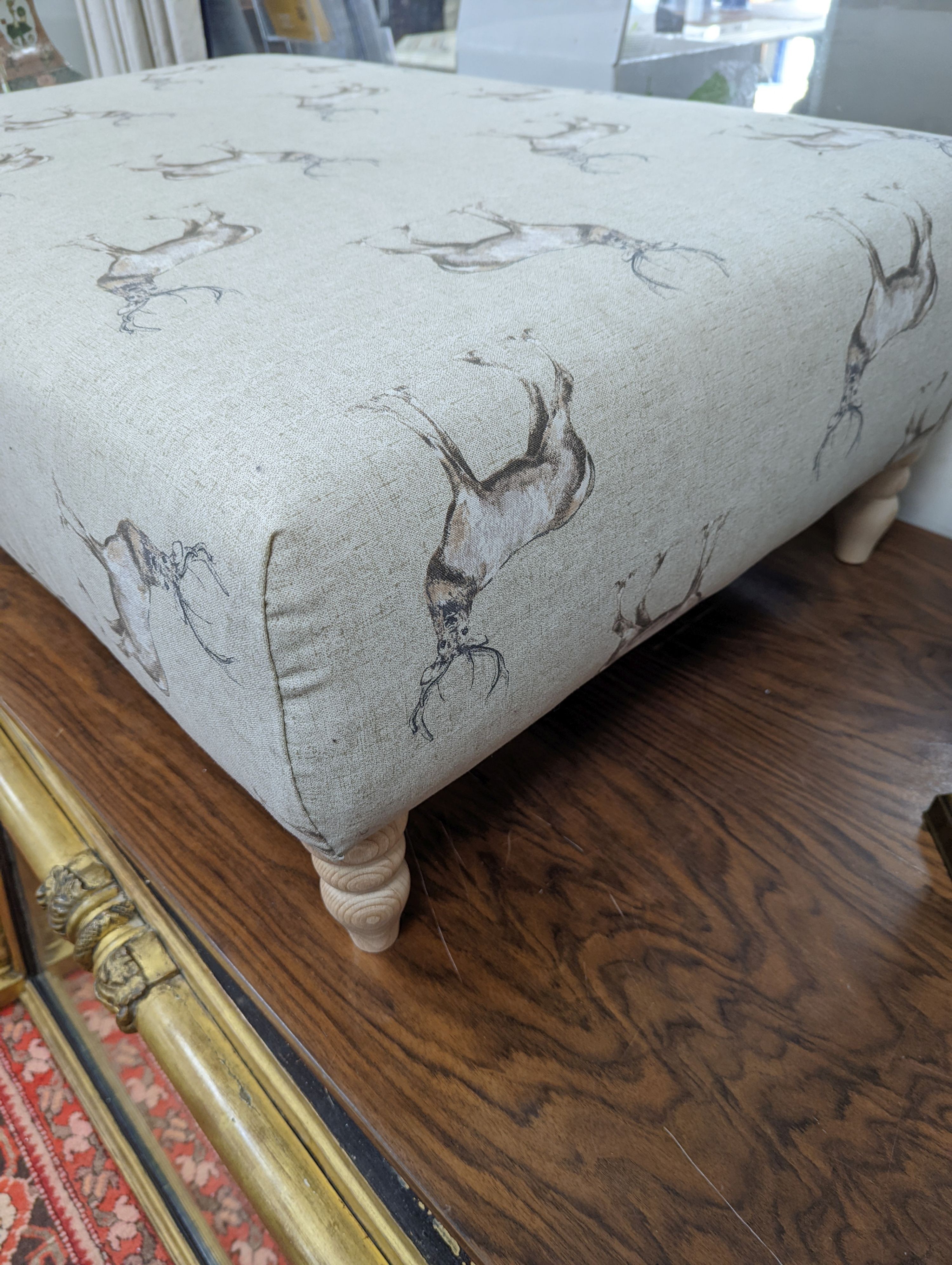 A large contemporary rectangular footstool / coffee table upholstered in stag print fabric on turned beech feet, length 107cm, depth 72cm, height 38cm